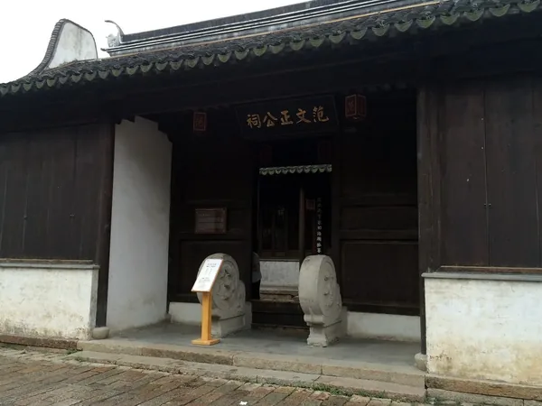 A recessed timber entrance and stone guardians at the Fan Zhongyan ancestral hall in Huishan.