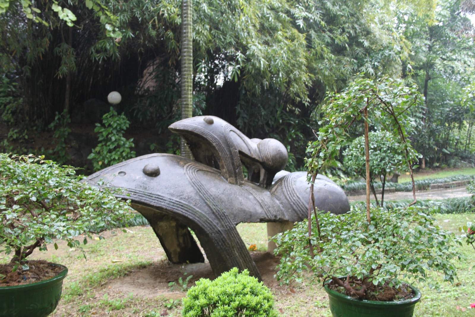 Deux sculptures géantes de grenouilles se dressent parmi les plantes d’un jardin.