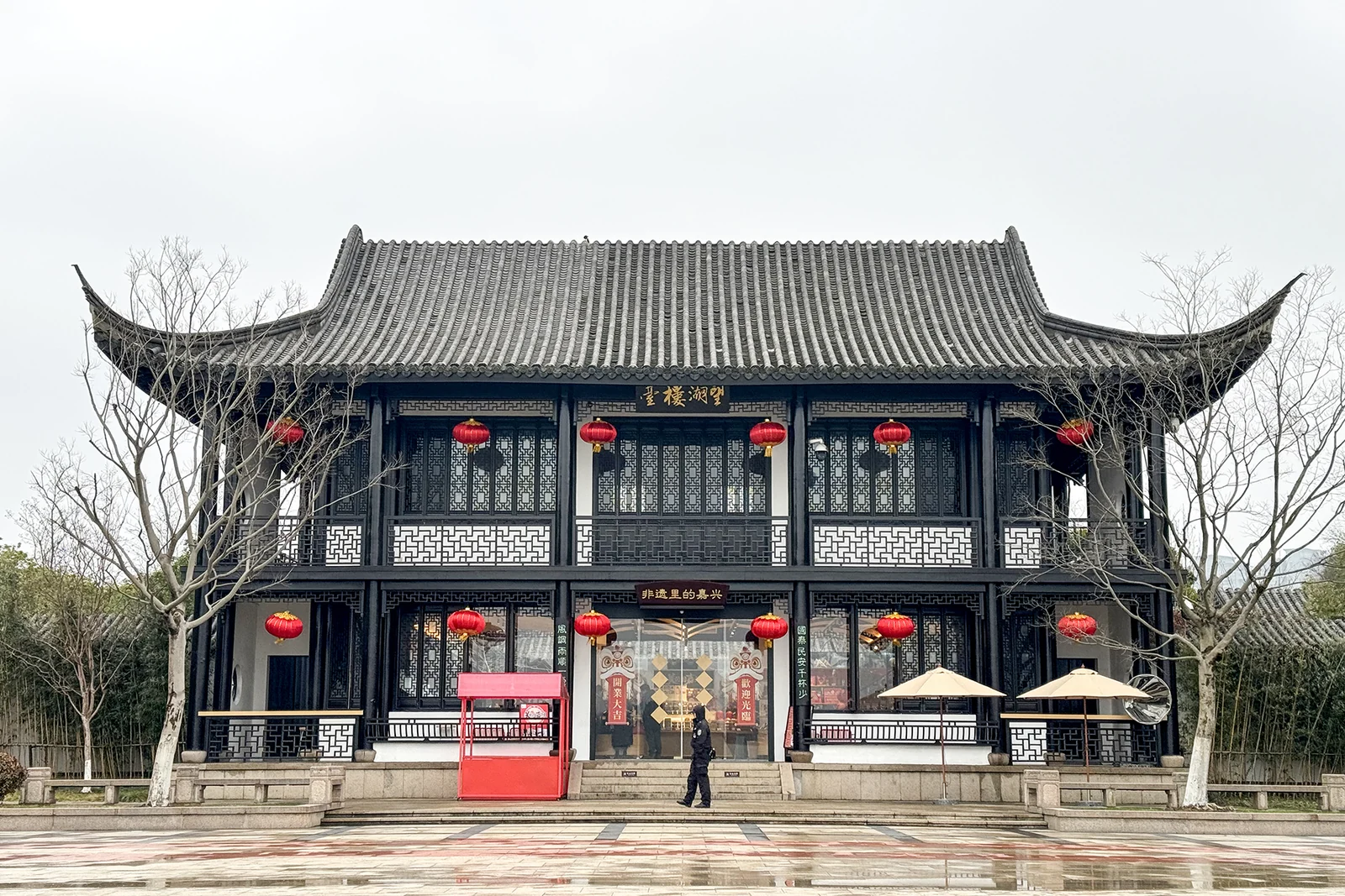 Der Wanghu-Pavillon hat eine dunkle Holzfassade, nach oben geschwungene Dachecken und rote Laternen.