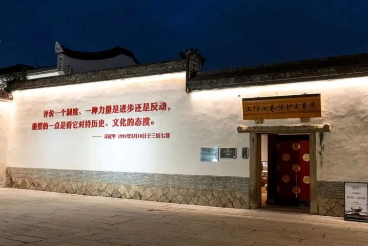 鞍の形の輪郭を持つ白い歴史的な壁が、明かりの灯る展示入口を囲む。