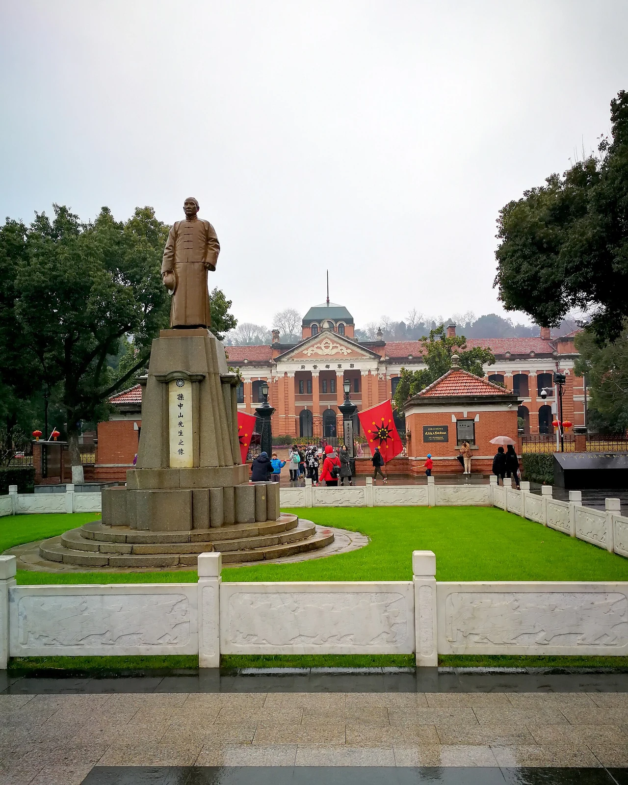The statue of Sun Yat-sen stands on its pedestal before the red-brick museum hall and revolutionary flags.