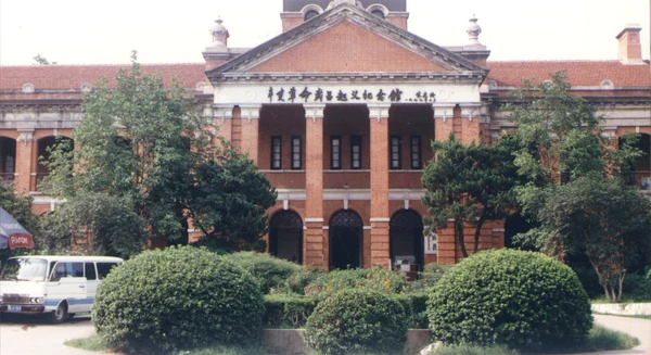 El edificio de ladrillo rojo del Museo del Levantamiento de Wuchang, con el rótulo del frontón sobre un seto recortado.