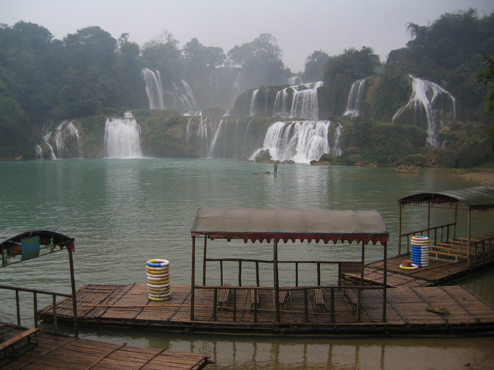 Tourist bamboo rafts float below the broad cascades of Detian waterfall.