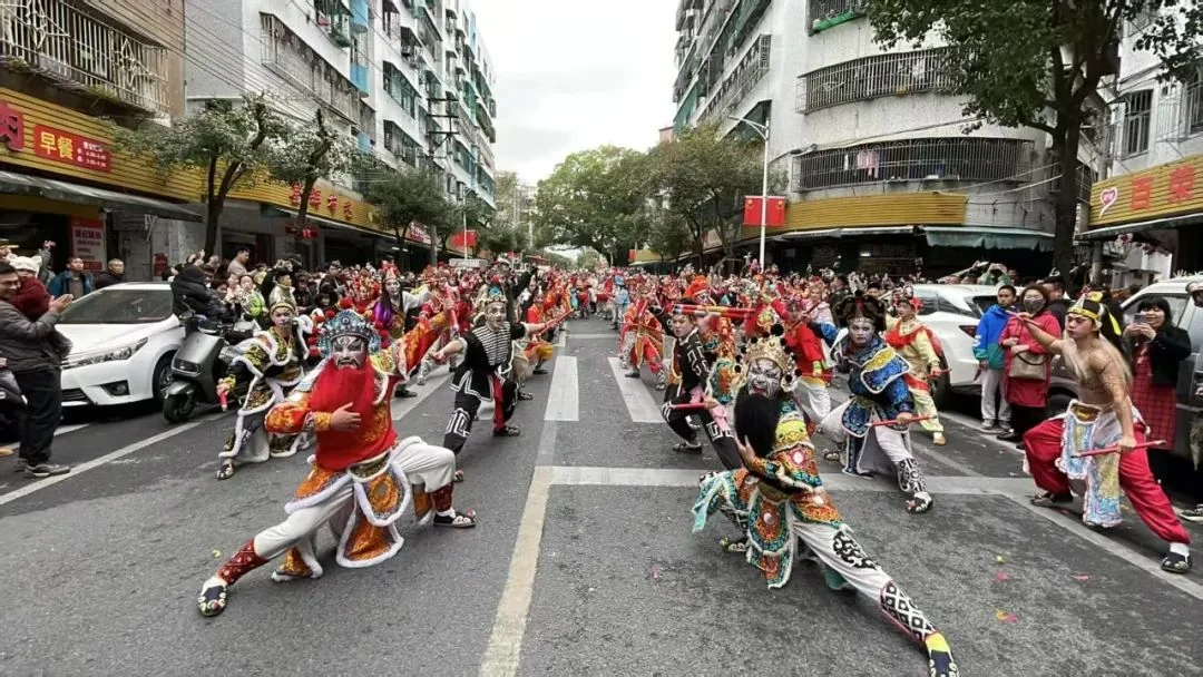Nas festas do Ano-Novo de 2025 em Shantou, artistas de rua com máscaras pintadas e trajes estampados se agacham com bastões de madeira.