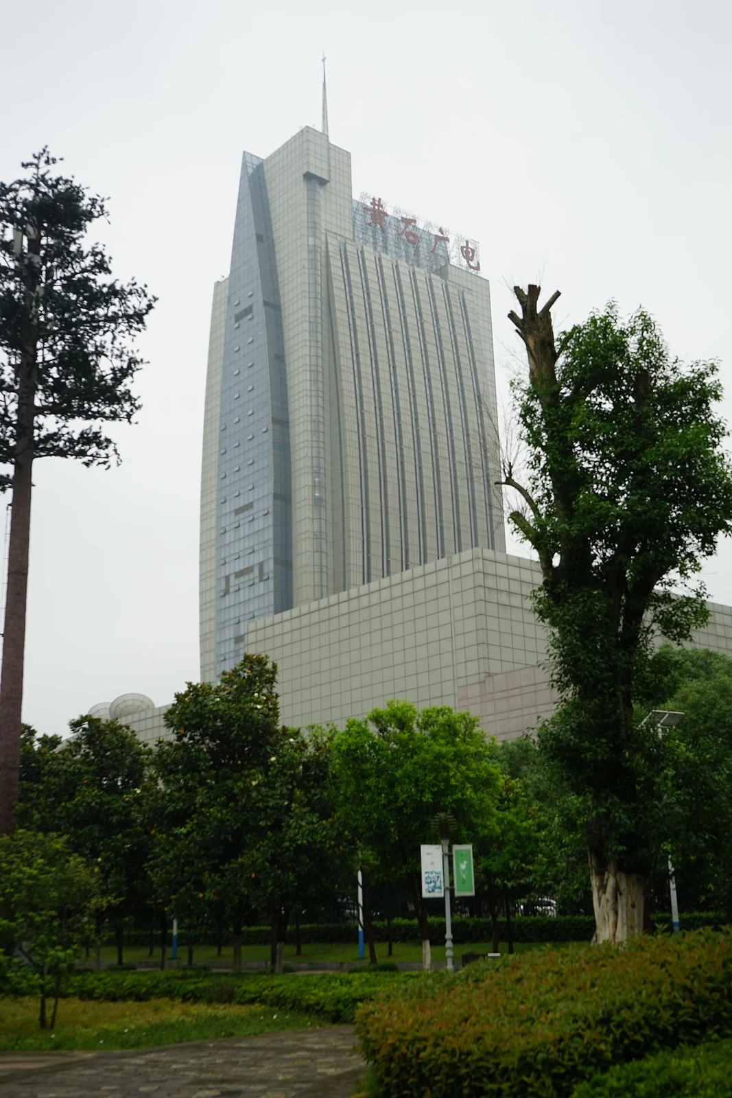 黄石:高耸的黄石广播电视大楼,玻璃幕墙从树梢间升起。