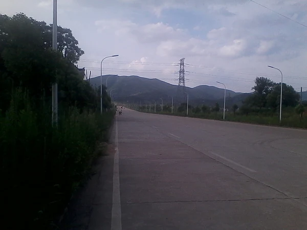 Huangshi: una carretera ancha por la zona industrial del Monte Dorado, con colinas detrás.