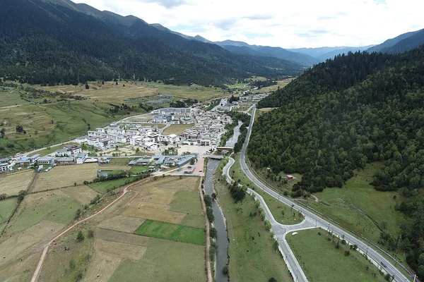 Luftaufnahme des Marktes Lulang und einer Straße im Bergtal