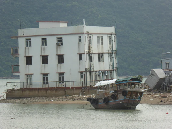 Ein Stelzenhaus und ein Boot am Ufer bei Niedrigwasser in Tai O.