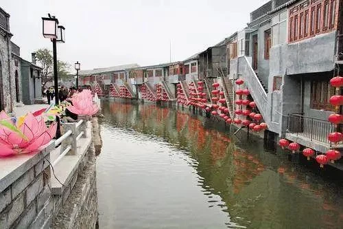 一段水道穿過民居之間，岸邊布有蓮花形燈飾。