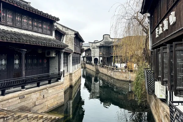White walls and timber-fronted buildings face a narrow watercourse in Yuehe.