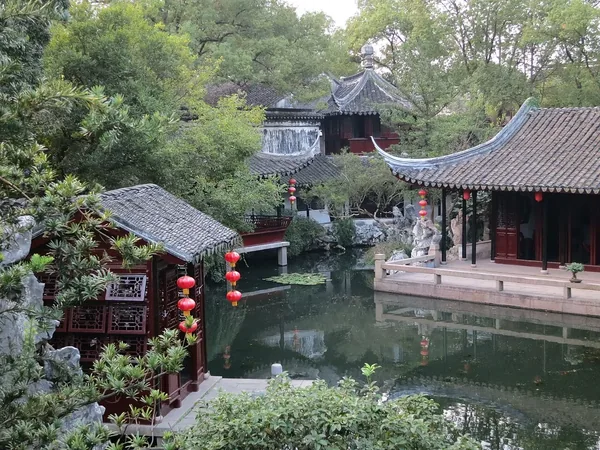 Pabellones de tejado curvo y galerías cubiertas reflejados en el estanque del Jardín Tuisi de Tongli.