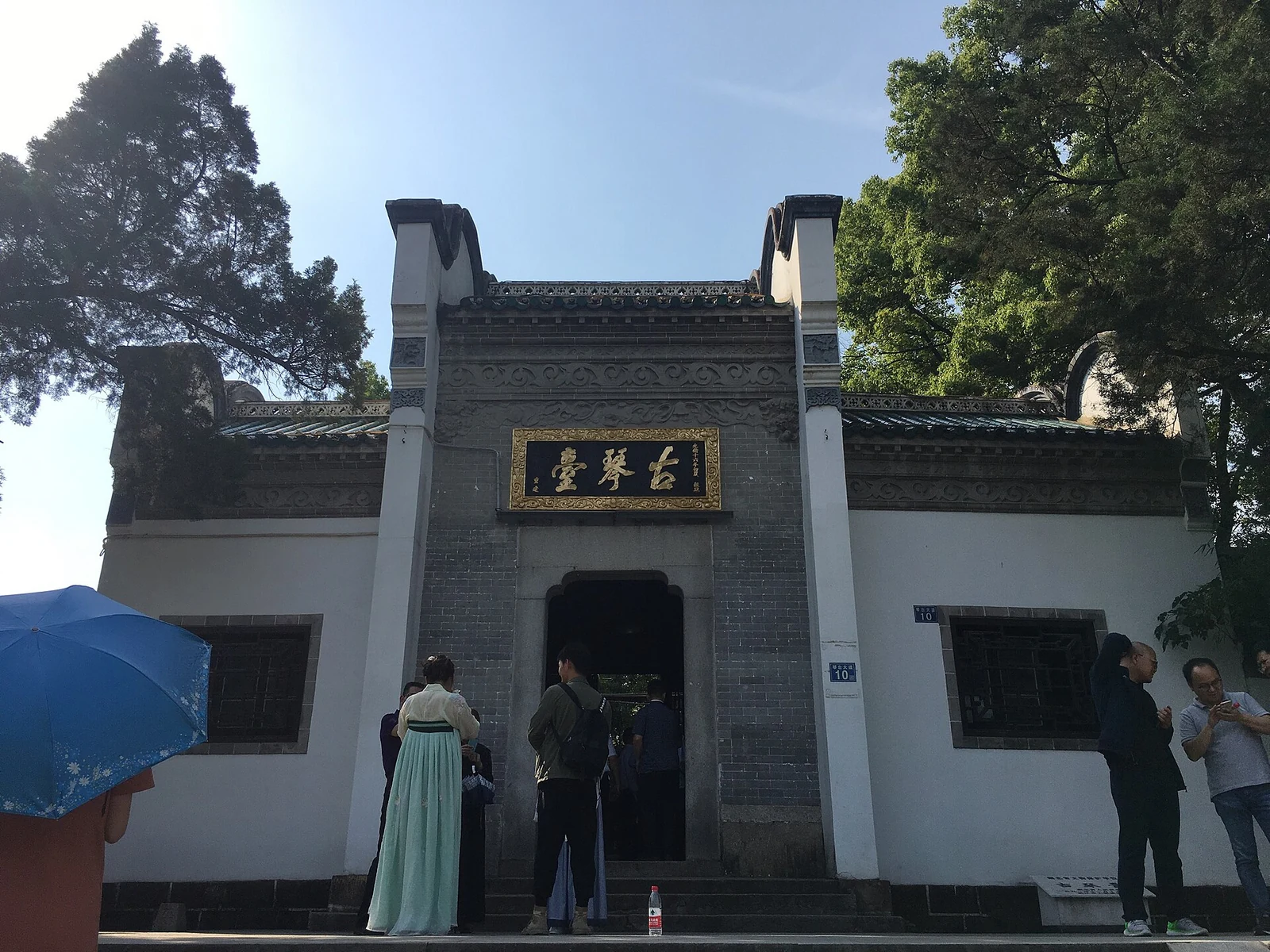 古琴台的砖砌门楼高悬金字匾额,游客正从门口走过。