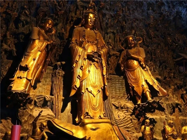 Detrás del Buda principal, Guanyin se alza en un paisaje esculpido de rocas y pequeñas figuras.