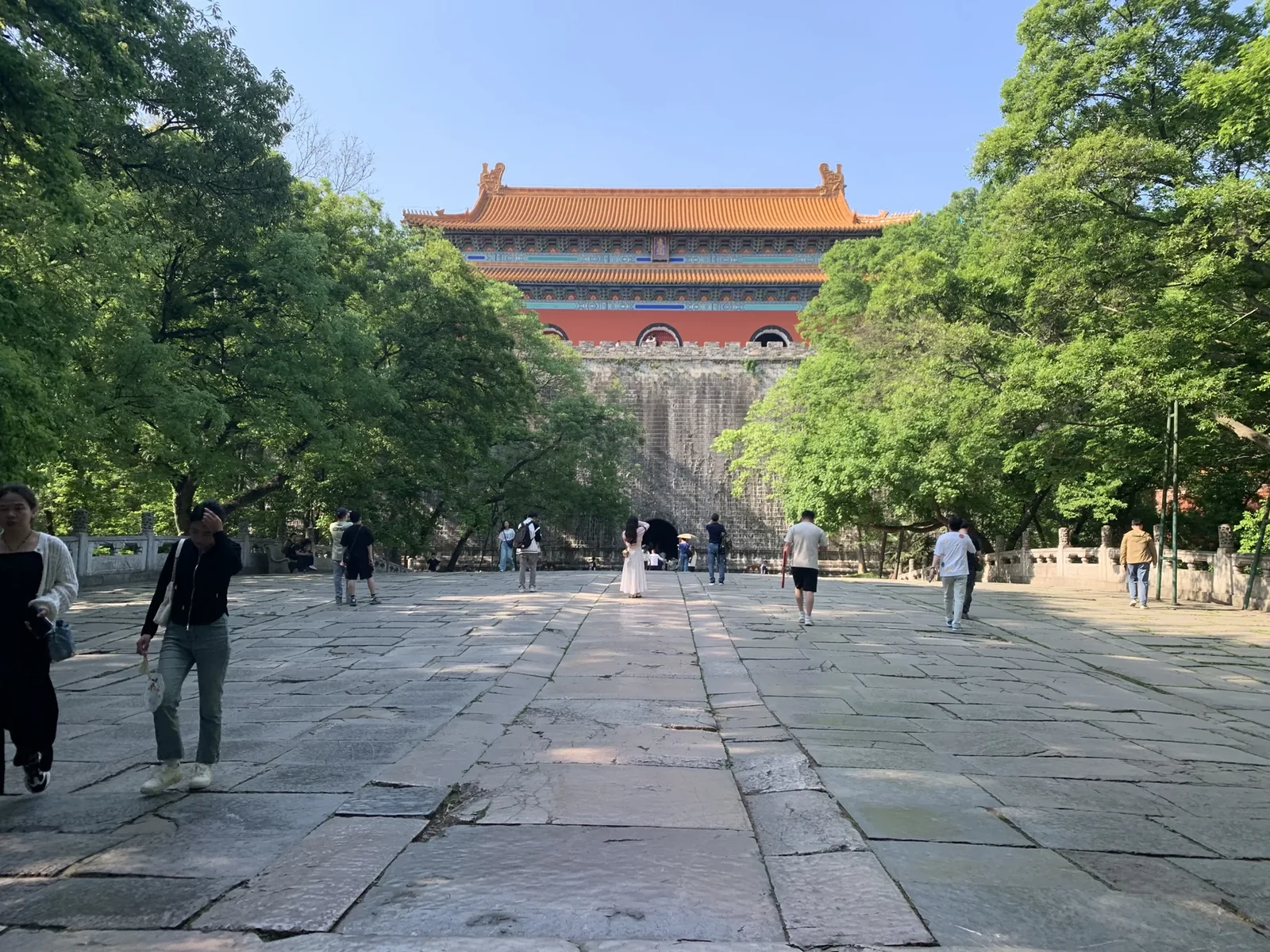 Visitors walk along a stone approach toward the red walls and yellow roof of Ming Xiaoling's Soul Tower.