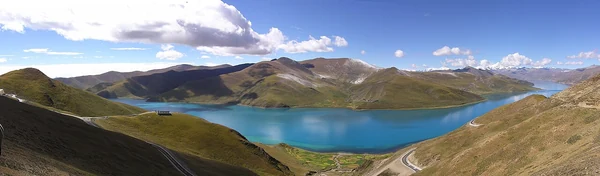 Una panorámica amplia muestra el agua del Yamdrok entre laderas montañosas.