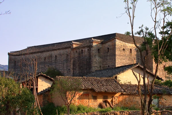 La haute enceinte rectangulaire de Yanyi Wei au-dessus des toits de tuiles à Longnan, dans le sud du Jiangxi. Photographie de 2017.