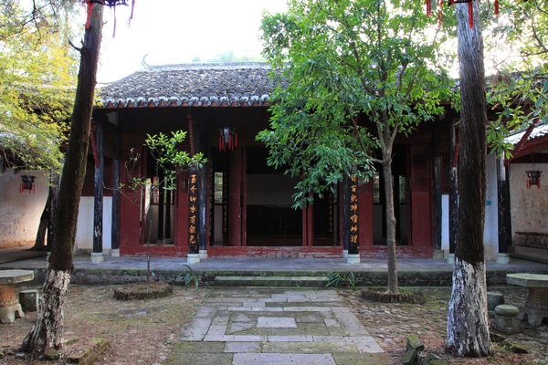 Le hall ouvert de l’académie Ehu, encadré d’arbres et de colonnes rouges.