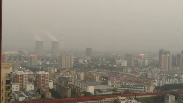 Jingmen: la línea de horizonte de la ciudad en la niebla, con chimeneas y bloques de tejado rojo.