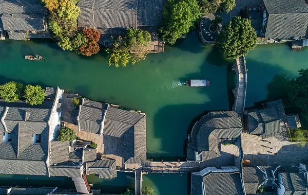 An overhead view of Wuzhen shows tiled roofs, a narrow canal and a small bridge.