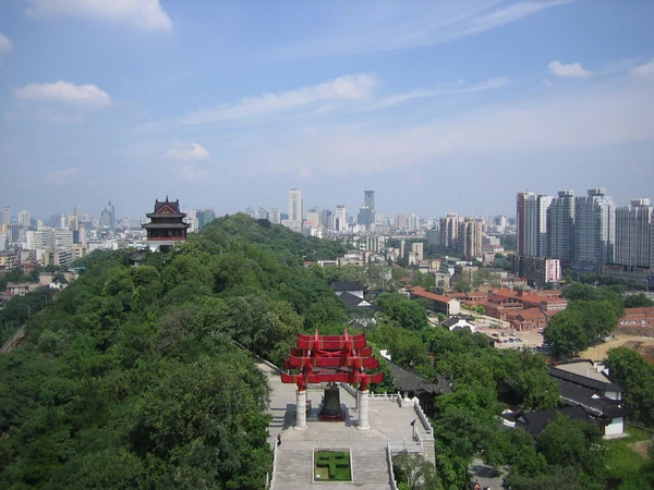 La Torre de la Grulla Amarilla sobre la colina se eleva por encima del pabellón rojo, con el horizonte de Wuhan al fondo.