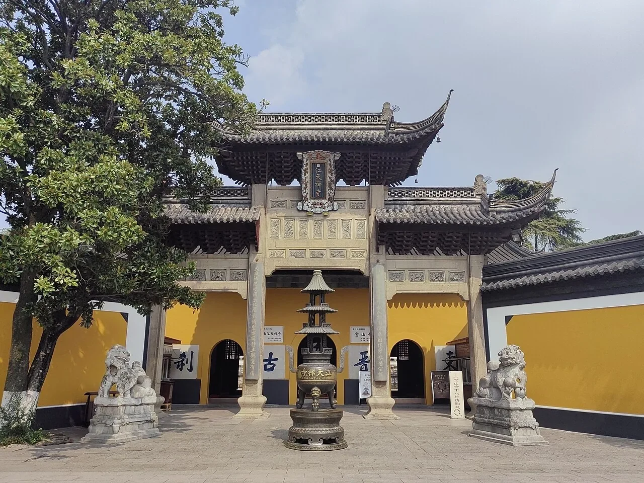 기와지붕과 돌 수호상을 갖춘 진산사의 노란 벽 입구 문.