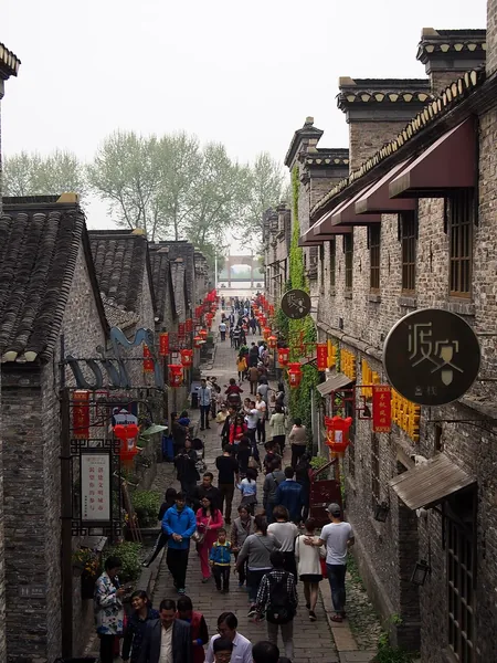 Visitors walk through a narrow old street lined with traditional buildings and red lanterns in Xijin Ferry.