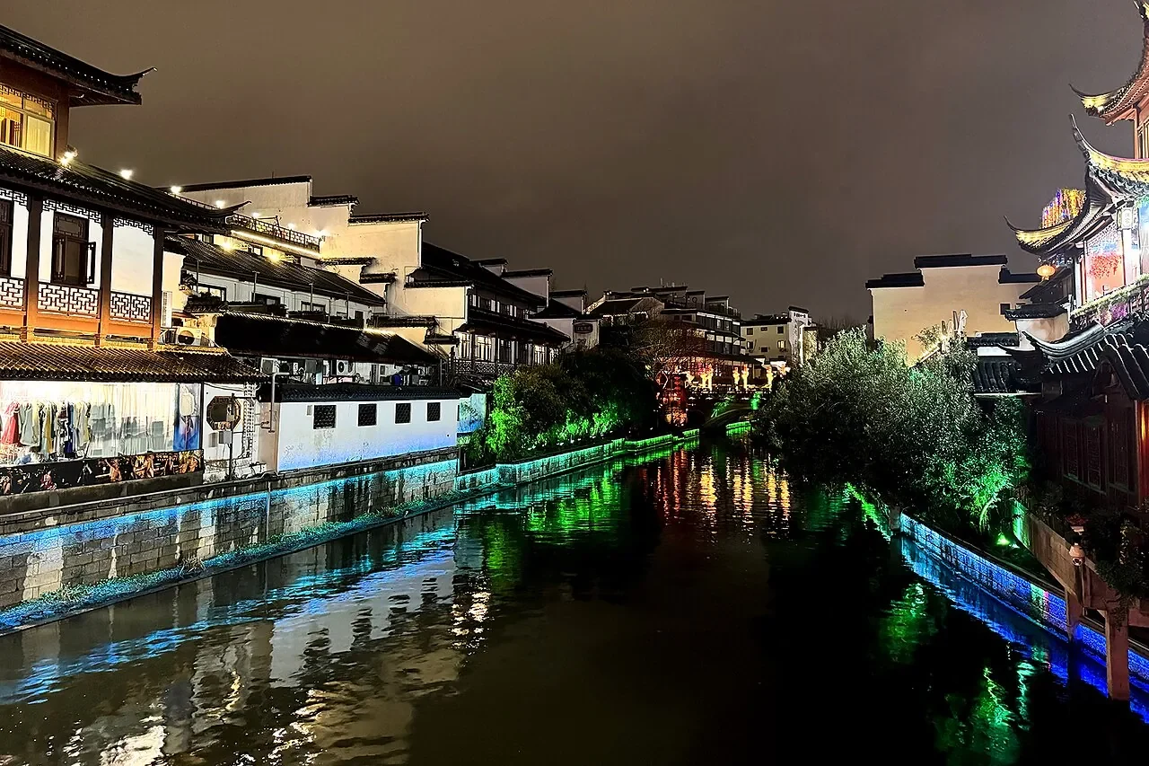夜の秦淮河に映る、照明を浴びた白い建物と色とりどりの光。