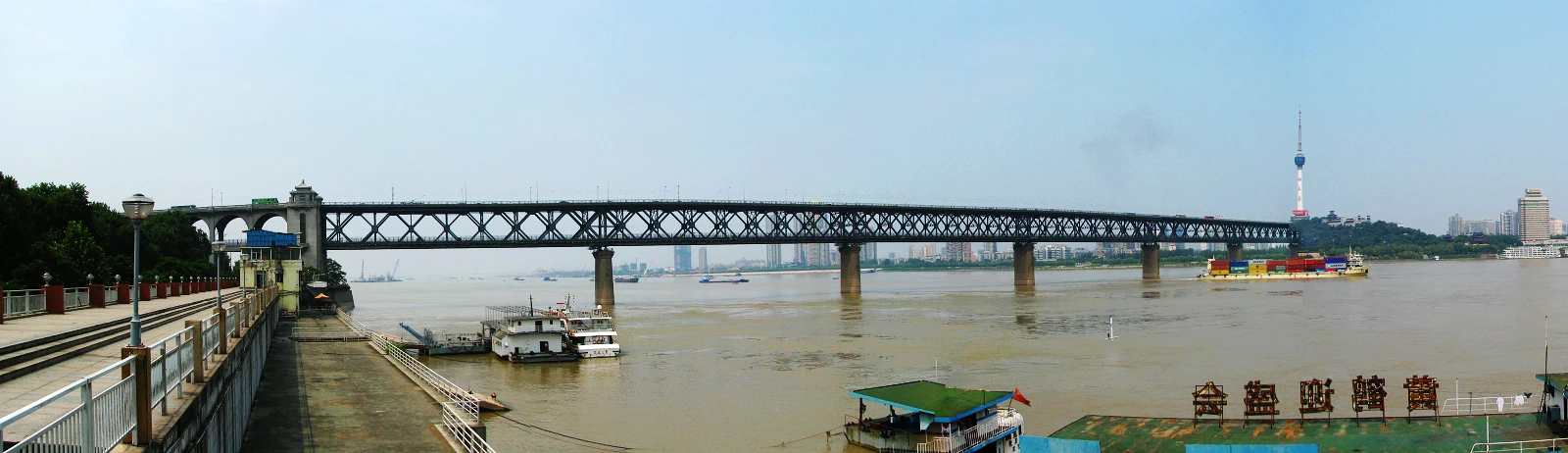 El puente del Yangtsé en Wuhan, con sus celosías de acero y la cabeza de puente, y barcazas debajo.