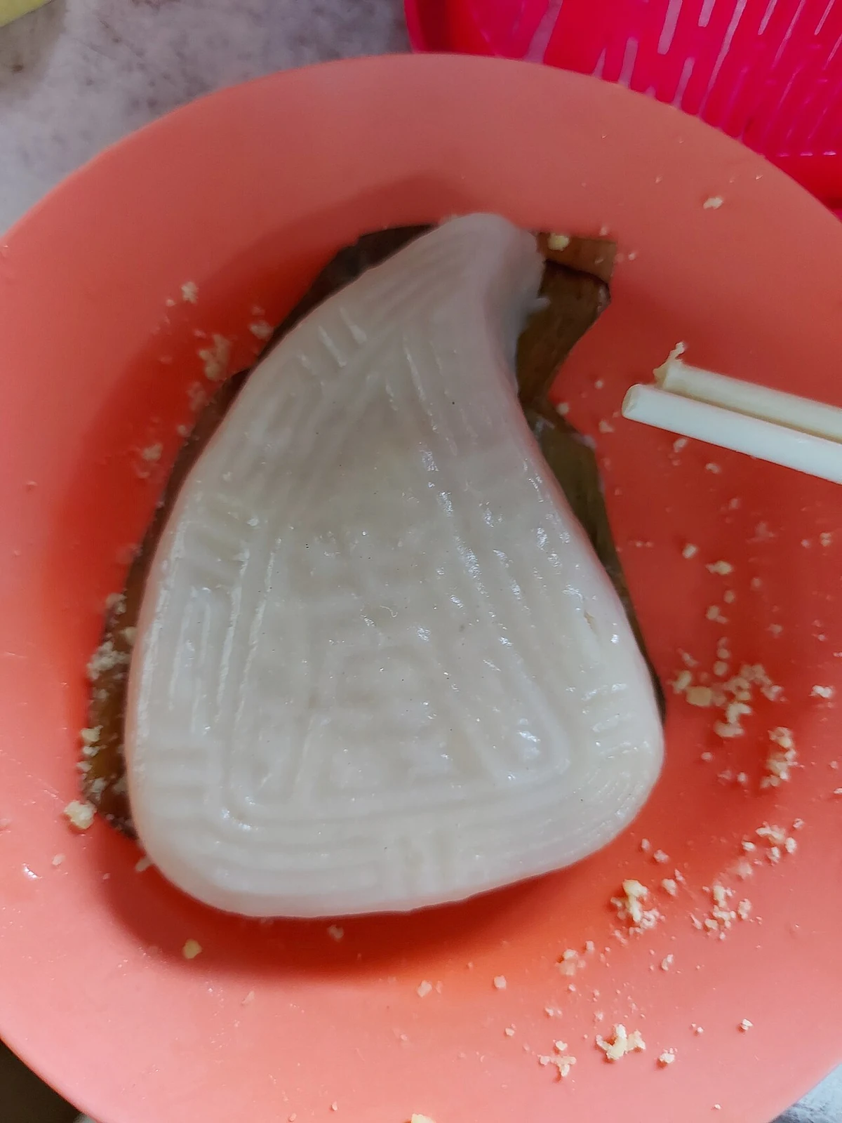 Gâteau de riz blanc en forme de pêche dans un bol rouge.