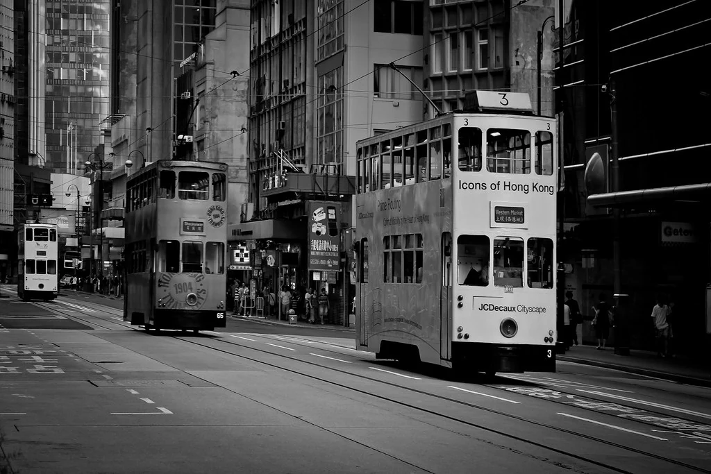 Zwei Doppeldecker-Straßenbahnen begegnen sich auf einer Straße in Hongkong.