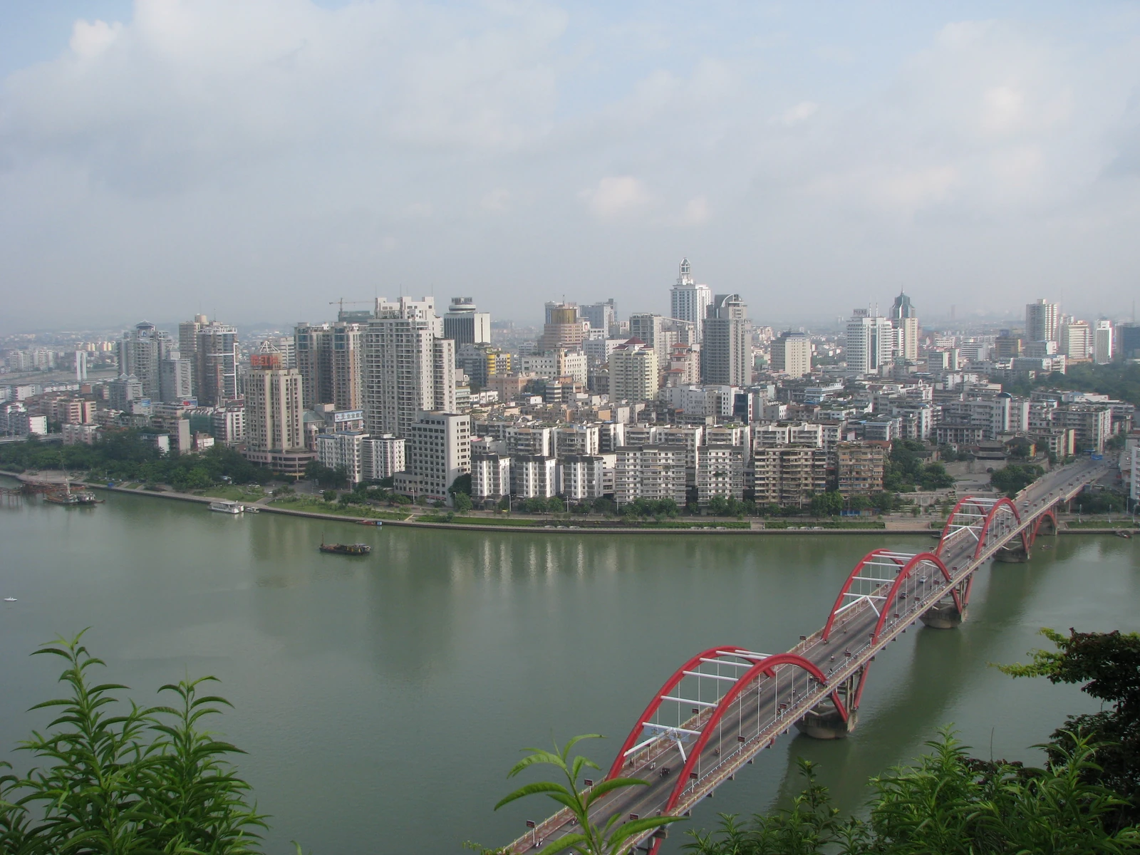 Edificios altos y un puente rojo bordean una amplia curva del río en Liuzhou.
