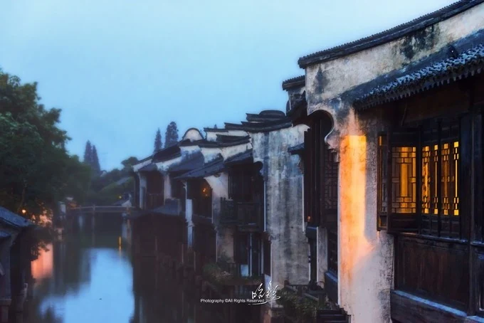 烏鎮安靜的河道上方，亮著燈的窗戶與白牆緊貼水面。