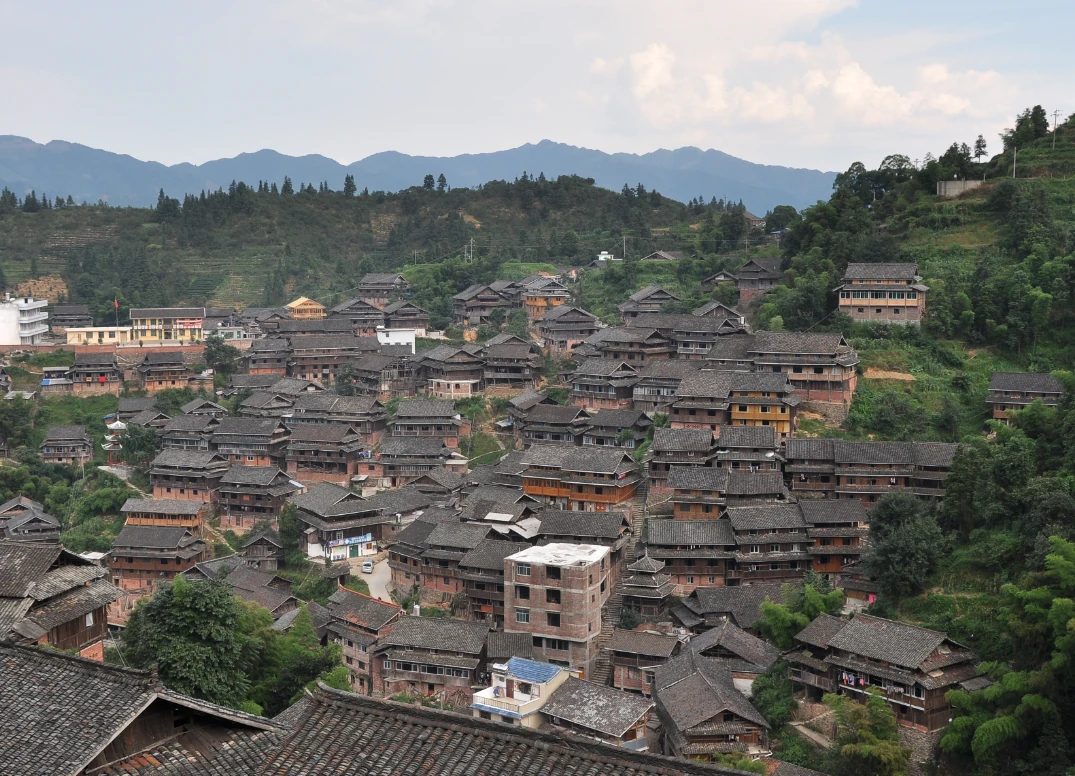 Des maisons en bois et des toits de tuiles couvrent les pentes d’un village de montagne.
