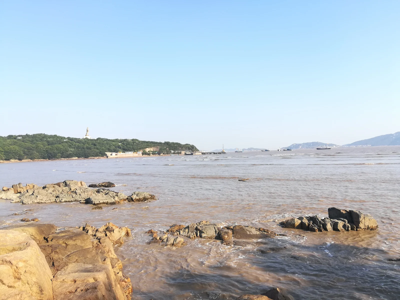 普陀島の岩場と木々に覆われた岬。その向こうに海と島々が広がります。
