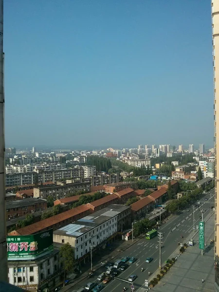 Suizhou: der Blick die Qingnian Road hinunter, mit niedrigen rotbedachten Blöcken und der Skyline dahinter.