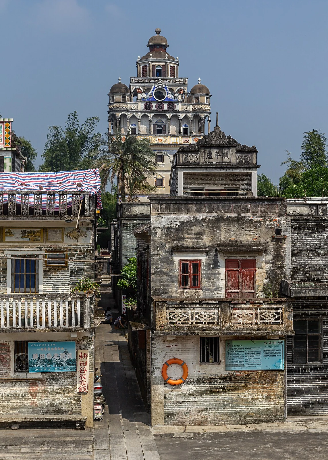 The many-storey Ruishi Lou rises above a village lane and nearby houses.