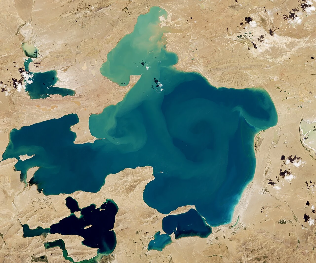 Естественный цветной снимок Селин-Цо со спутника Landsat: бирюзовые и тёмно-синие воды образуют разветвлённые очертания среди светлого плато и малых озёр.