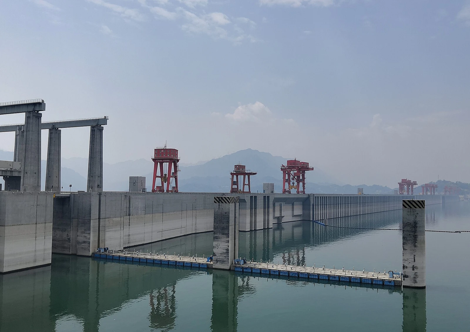 三峡大坝：坝顶上的红色门式起重机，以及库区水面上的船闸浮桥。