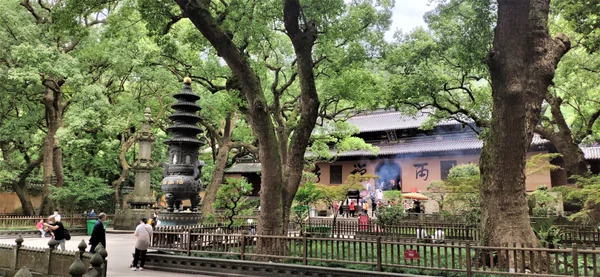 Fayu Temple’s hall, incense vessel and stone pagoda beneath mature trees on Putuo Island.