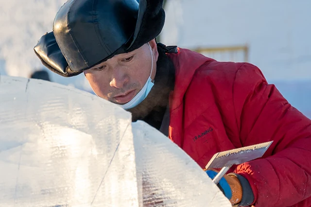 Arbeiter bearbeitet die Oberfläche eines Eisblocks